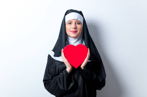 jeune nonne souriante avec boîte forme coeur - nun sign holding women photos et images de collection