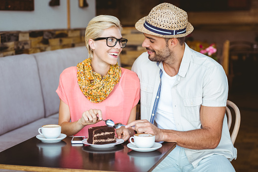 Cute couple on a date eating a piece of chocolate cake at the cafe