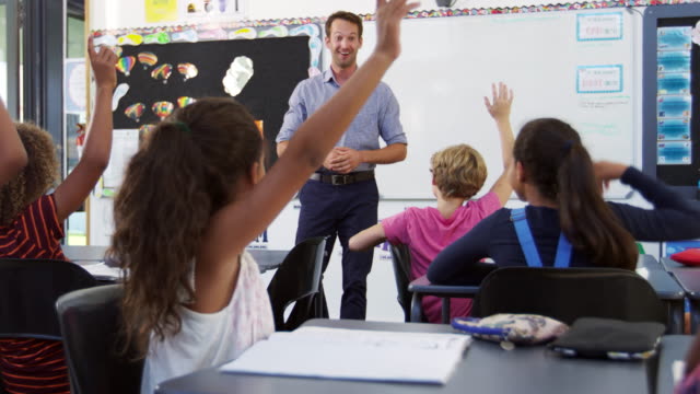 School kids raising hands in an elementary school class