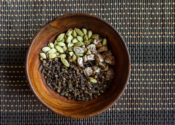 Cardamon, cloves and areca nuts in wooden bowl