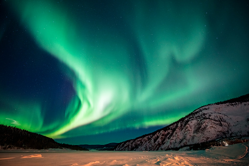 Spectacular display of Aurora borealis forming a green band over snowy winter,Yukon Territory,Canada.