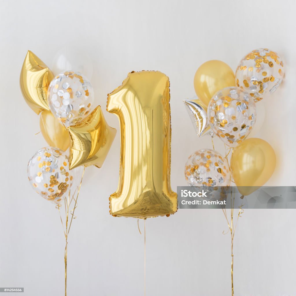 Decoration for 1 years birthday, anniversary Decoration for birthday, anniversary, celebration of the first anniversary, white background and gold balloons First Birthday Stock Photo