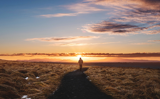 a man walking alone on footpath, Landscaped of Iceland, at Hvitserkur in Sunset