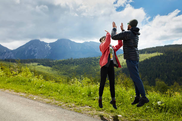 Summer view of mountains. Jumping and looking at each other, high five