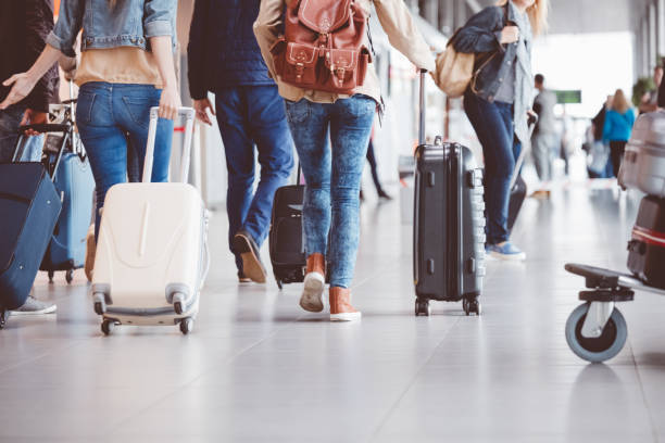 Passengers walking in the airport terminal Low angle rear view of passengers walking in the airport terminal. People with luggage in airport. world travel stock pictures, royalty-free photos & images