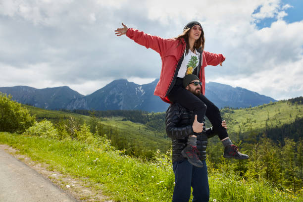 istock Smiling woman sitting on man's back. Mountain landscape. 814271258