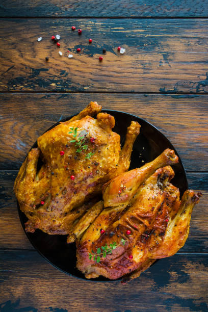 istock Crispy roasted garlic chicken with fresh thyme on a black plate on the wooden rustic table, top view. 814282044