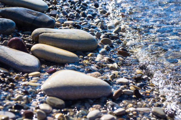 istock sea pebble beach with multicoloured stones, waves with foam 814304306