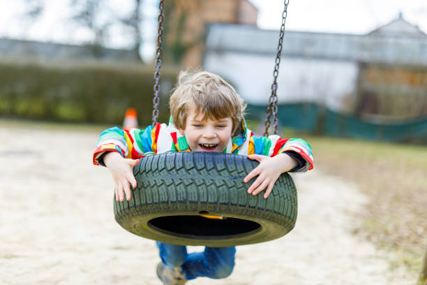 istock Funny kid boy having fun with chain swing on outdoor playground 814304702