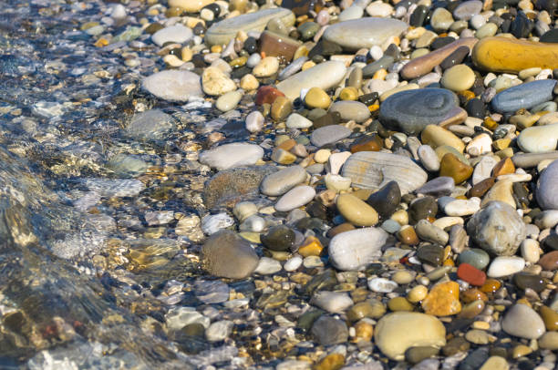 istock sea pebble beach with multicoloured stones, waves with foam 814306846