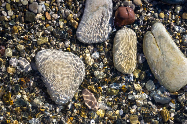 istock sea pebble beach with multicoloured stones, waves with foam 814307314