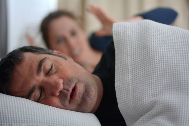 Woman suffers from her male partner snoring in bed stock photo