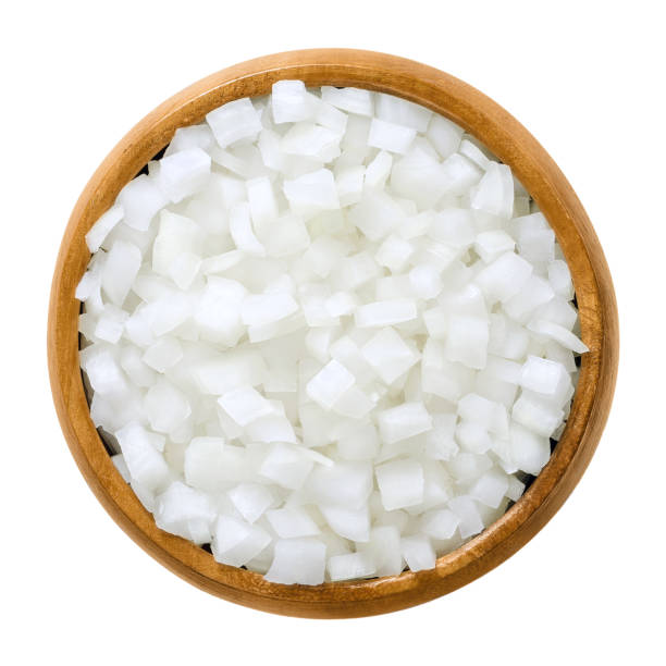White onion cubes in wooden bowl over white White onion cubes in wooden bowl. Chopped fresh, raw Allium cepa, also bulb or common onion. Vegetable, ingredient and staple food. Isolated macro food photo close up from above on white background. onion stock pictures, royalty-free photos & images
