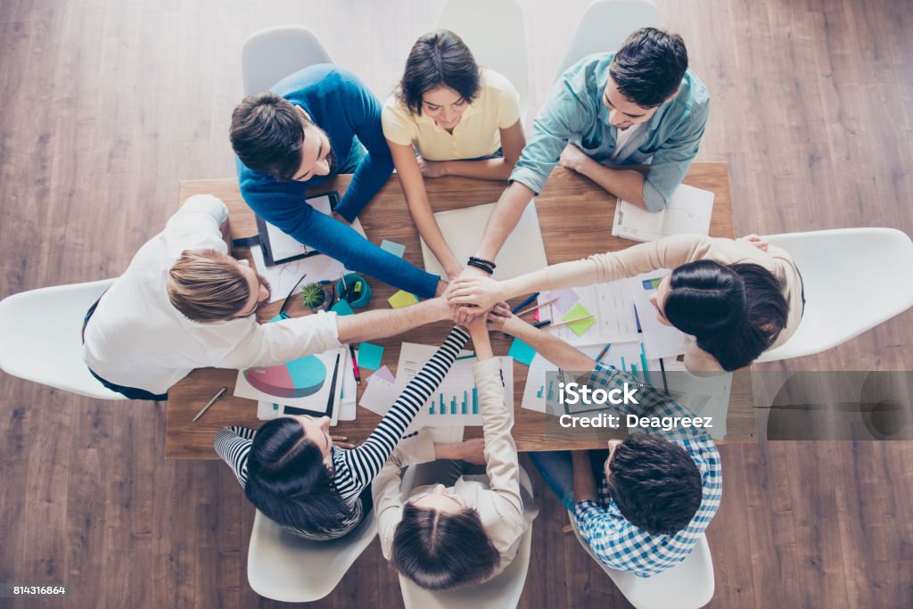 All together! Conception of successful teambuilding. Topview of businesspeople putting their hands on top of each other in nice light workstation, wearing casual clothes Entrepreneur Stock Photo