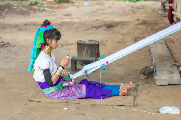 Long Neck Village in Thailand CHIANG MAI, THAILAND - July 10, 2017: Karen hill-tribe (Long Neck) woman weaving fabrics for a living at her house in a tribe near Chiang Mai in Northern Thailand. kayan neck rings stock pictures, royalty-free photos & images