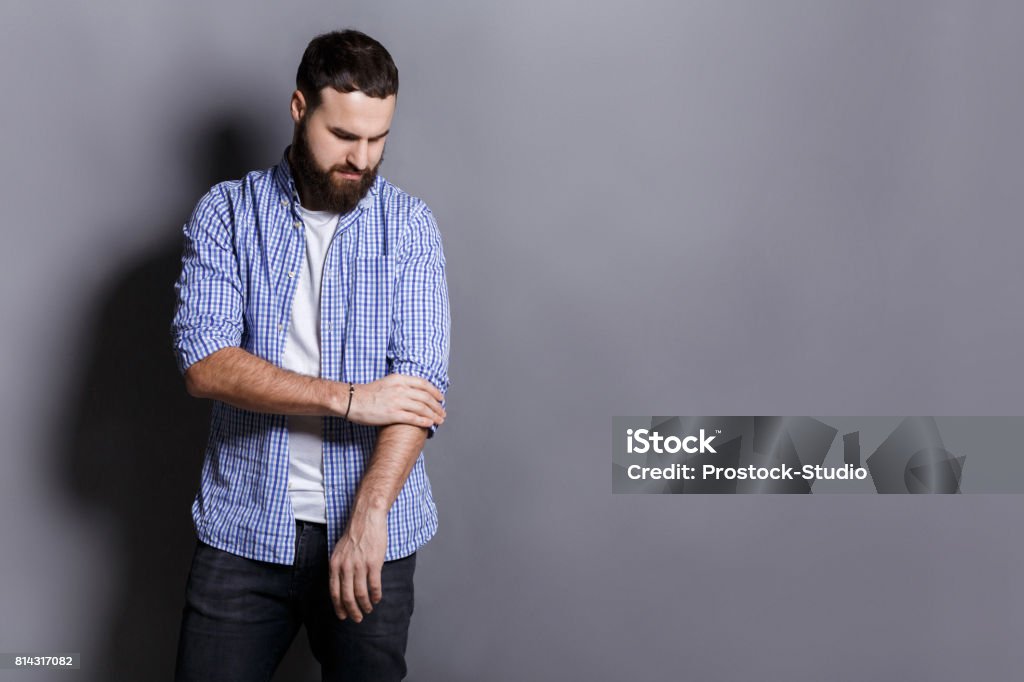 Bearded man in shirt adjusting sleeves copy space Bearded man preparing to work hard, adjusting sleeves, copy space, gray studio background Rolling Stock Photo