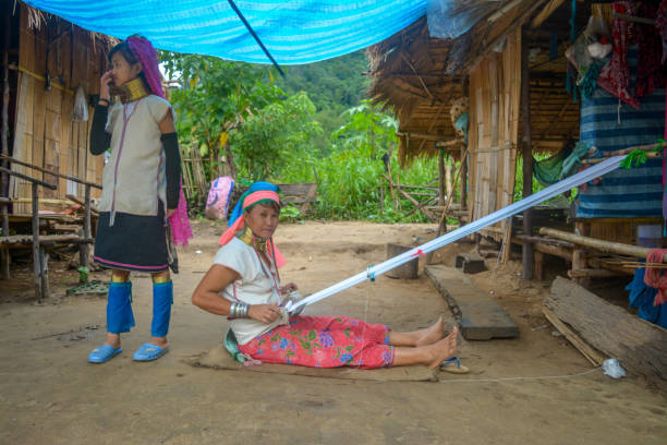 Long Neck Village in Thailand CHIANG MAI, THAILAND - July 10, 2017: Karen hill-tribe (Long Neck) woman weaving fabrics for a living at her house in a tribe near Chiang Mai in Northern Thailand. kayan neck rings stock pictures, royalty-free photos & images
