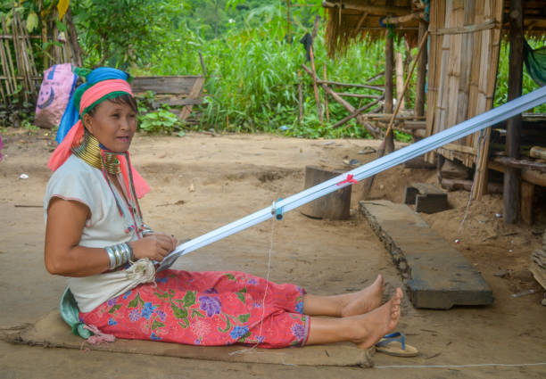 Long Neck Village in Thailand CHIANG MAI, THAILAND - July 10, 2017: Karen hill-tribe (Long Neck) woman weaving fabrics for a living at her house in a tribe near Chiang Mai in Northern Thailand. kayan neck rings stock pictures, royalty-free photos & images
