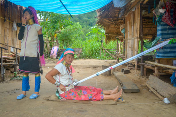 Long Neck Village in Thailand CHIANG MAI, THAILAND - July 10, 2017: Karen hill-tribe (Long Neck) woman weaving fabrics for a living at her house in a tribe near Chiang Mai in Northern Thailand. kayan neck rings stock pictures, royalty-free photos & images