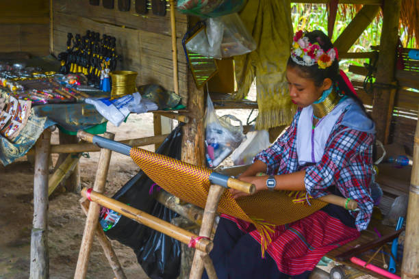 Long Neck Village in Thailand CHIANG MAI, THAILAND - July 10, 2017: Karen hill-tribe (Long Neck) woman weaving fabrics for a living at her house in a tribe near Chiang Mai in Northern Thailand. kayan neck rings stock pictures, royalty-free photos & images