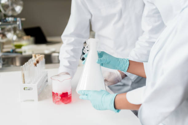 istock Close-up partial view of scientists making experiment with reagent and flasks 814326254