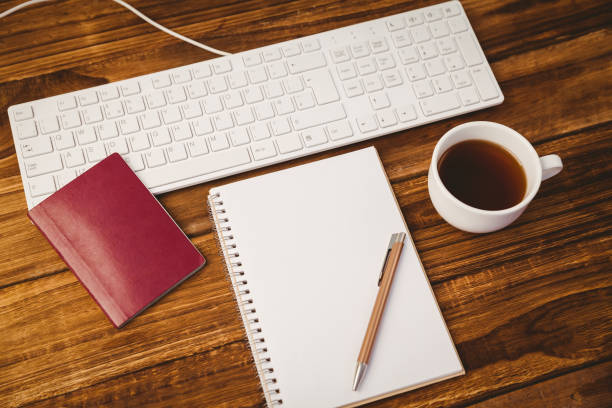 istock Pen on notepad next to cup of coffee passport and keyboard 814328690