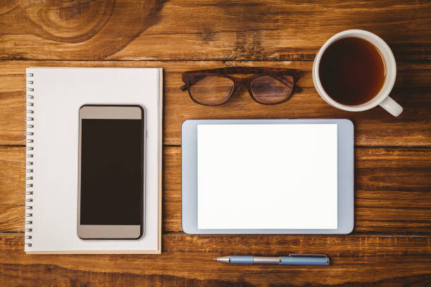 istock Smartphone on notepad next to tablet and glasses and cup of coffee 814331532