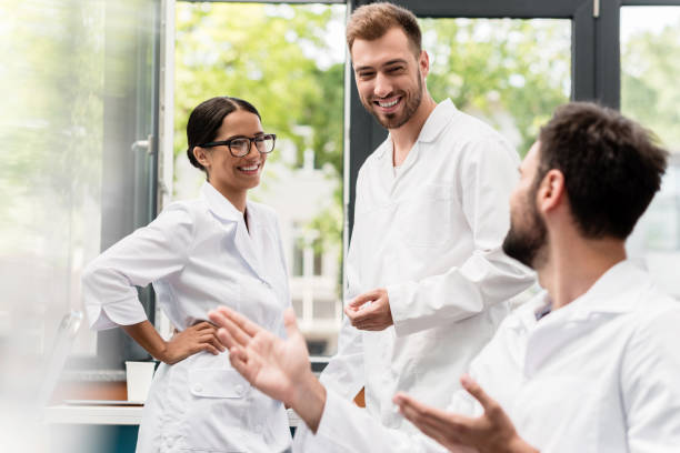 Team of professional scientists in white coats smiling and talking in laboratory Team of professional scientists in white coats smiling and talking in laboratory together for yes stock pictures, royalty-free photos & images