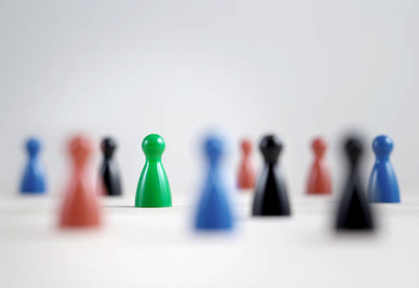 istock Many board game pawns on table, selective focus on the green one. Being brave, be yourself and originality concept. Diversity and tolerance. 814336062