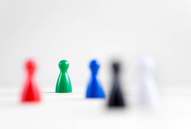 istock Many board game pawns on table, selective focus on the green one. Being brave, be yourself and originality concept. Diversity and tolerance. 814336112