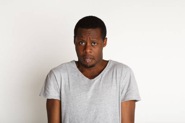 Scared and doubtful, facial expressions, black man Negative emotions. Black man expressing fear and hesitation, standing on white background, studio shot confusion raised eyebrows human face men stock pictures, royalty-free photos & images