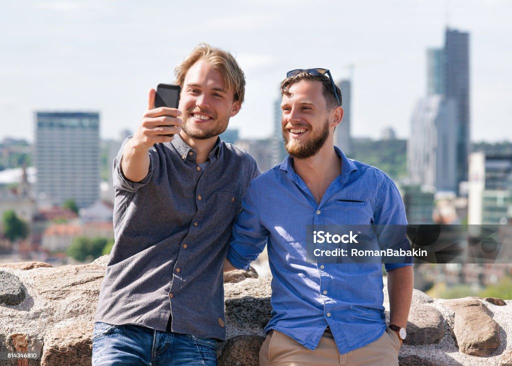 Jovens amigos caucasianos fazendo selfie no horizonte da cidade a sorrir - Foto de stock de Abraçar royalty-free