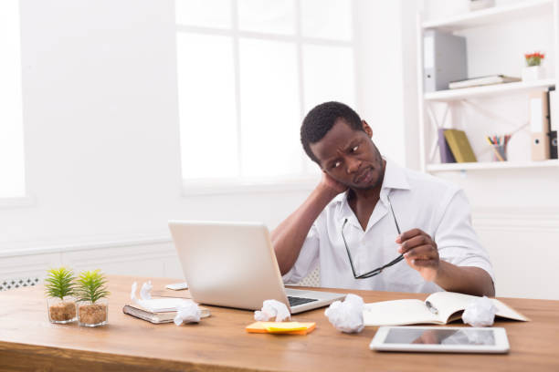 istock Overworked african-american employee in office, work with laptop 814347196