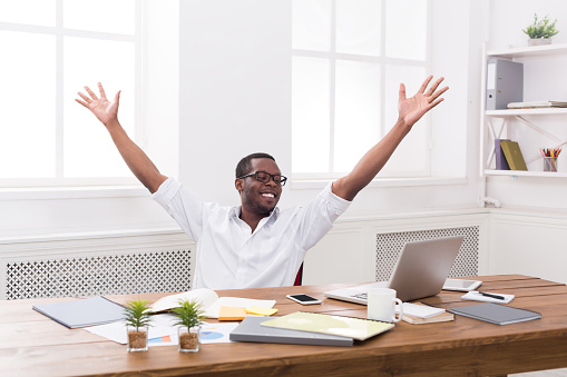 Happy excited businessman celebrate. Winner, black man in office with laptop