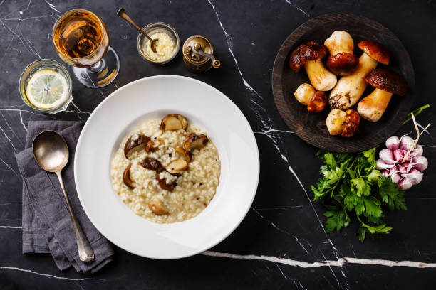 Risotto with porcini mushroom Risotto with porcini mushroom on plate and raw mushrooms on dark marble table background porcini mushroom stock pictures, royalty-free photos & images