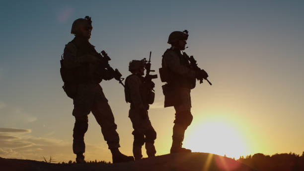 Squad of Three Fully Equipped and Armed Soldiers Standing on Hill in Desert Environment in Sunset Light. Squad of Three Fully Equipped and Armed Soldiers Standing on Hill in Desert Environment in Sunset Light. afghanistan army stock pictures, royalty-free photos & images