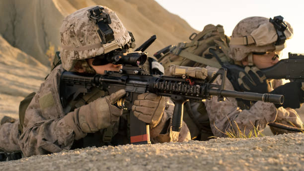 istock View on Soldiers Lie Down on the Hill, Aim through the Assault Rifle Scope in Desert Environment. 814367012
