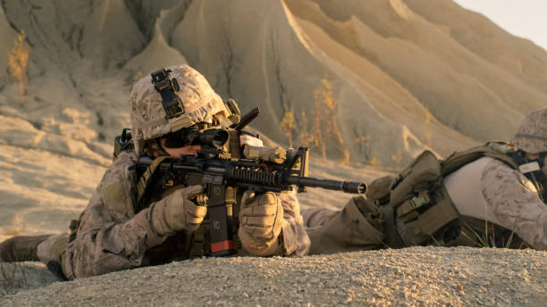 istock View on Soldier Lying Down on the Hill, Aiming through the Assault Rifle Scope in Desert Environment. 814367018
