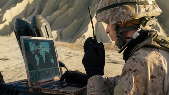 Soldado está usando el ordenador y Radio para la comunicación durante la operación militar en el desierto. photo