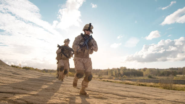 istock Squad of Fully Equipped and Armed Soldiers With Comander Ahead Running in Single File in the Desert. 814367376