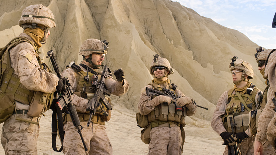 Tiro de equipado grupo de soldados de pie en un círculo y planificación de sus acciones antes de la operación militar en el desierto. photo
