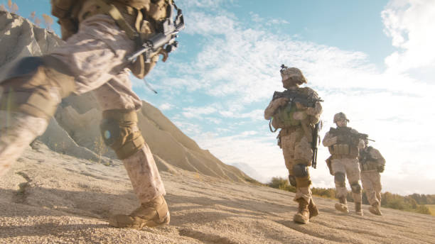 squad of fully equipped and armed soldiers moving in single file in the desert. - iraq conflict imagens e fotografias de stock