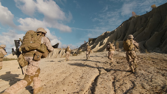 Tiro de una escuadra de soldados corriendo adelante y enemigo de atacar durante una operación militar en el desierto. photo