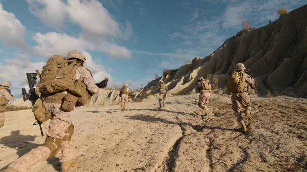 tiro de una escuadra de soldados corriendo adelante y enemigo de atacar durante una operación militar en el desierto. - guerra fotografías e imágenes de stock