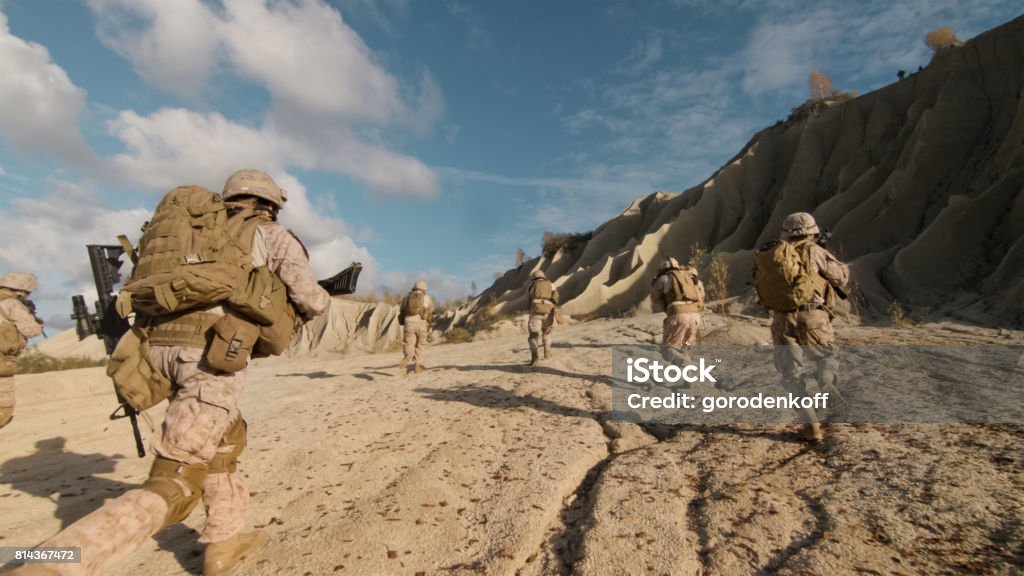 Shot of a Squad of Soldiers Running Forward and Atacking Enemy During Military Operation in the Desert. Afghanistan Stock Photo