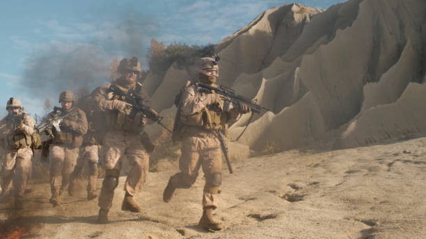 istock Squad of Fully Equipped, Armed Soldiers Running Through Black Smoke and Attacking During Military Operation in Desert. 814367510
