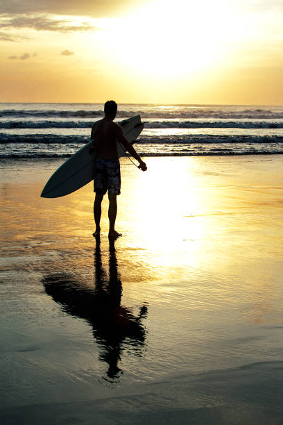 istock SURFER WITH SURFBOARD IN BALI, SUNSET KUTA BEACH 814386224