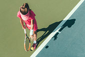 Young girl playing tennis, preparing to serve
