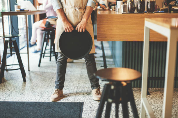 Waiter standing and holding serving tray next to the bar counter, low section.