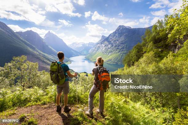 Dos Excursionistas En El Punto De Vista De Las Montañas Con El Lago Soleado De Verano Foto de stock y más banco de imágenes de Excursionismo